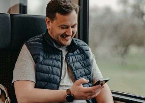 Mann liest im Zug Bibel auf seinem Handy